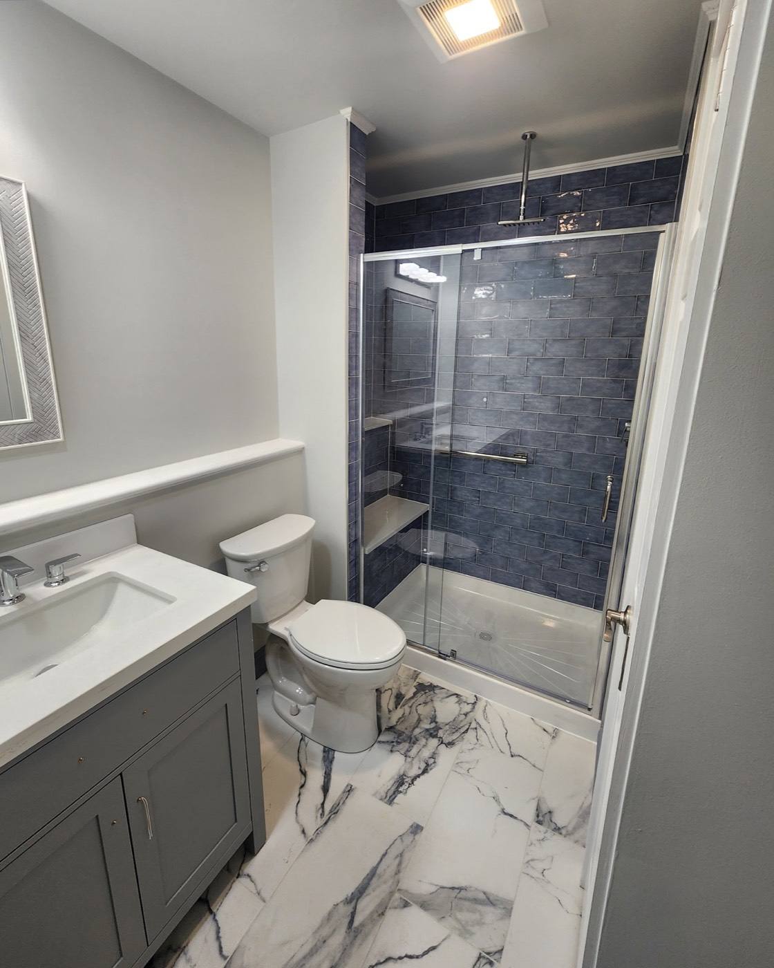 Navy tile shower with marble-look floor